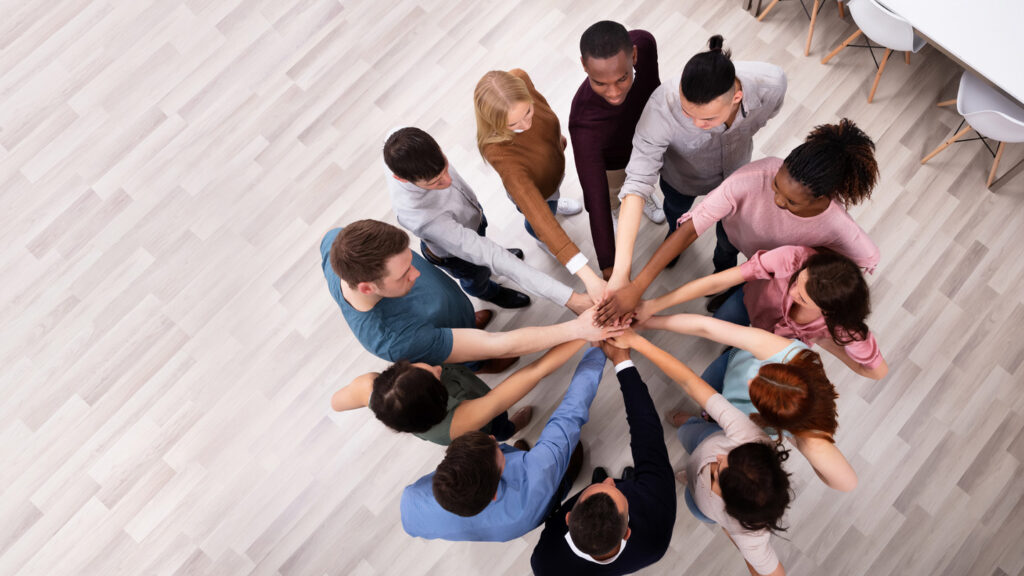 an overhead photo of a circle of people putting their hands in the center