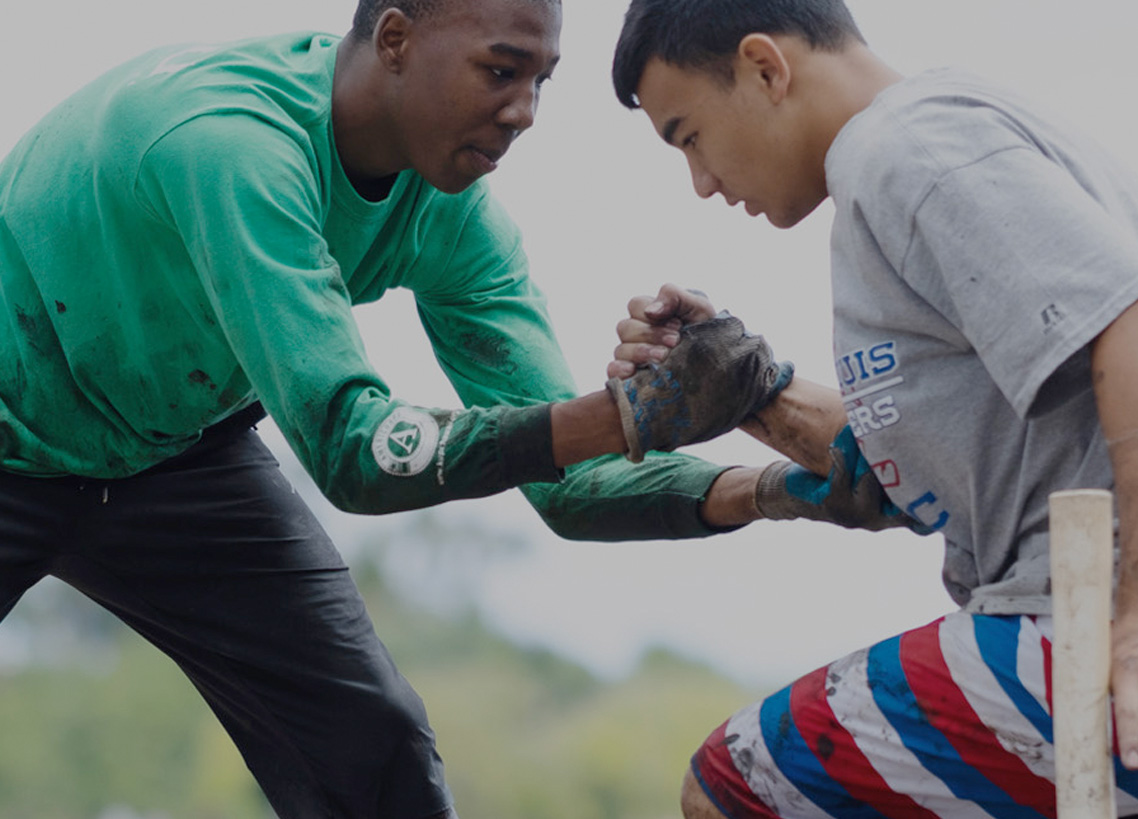 One young man helps another young man to his feet